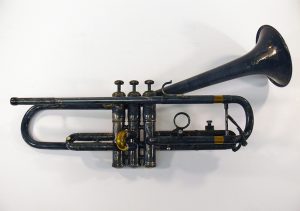 Used trumpet on white background; trumpet horn is bent upwards at a 30 degree angle.