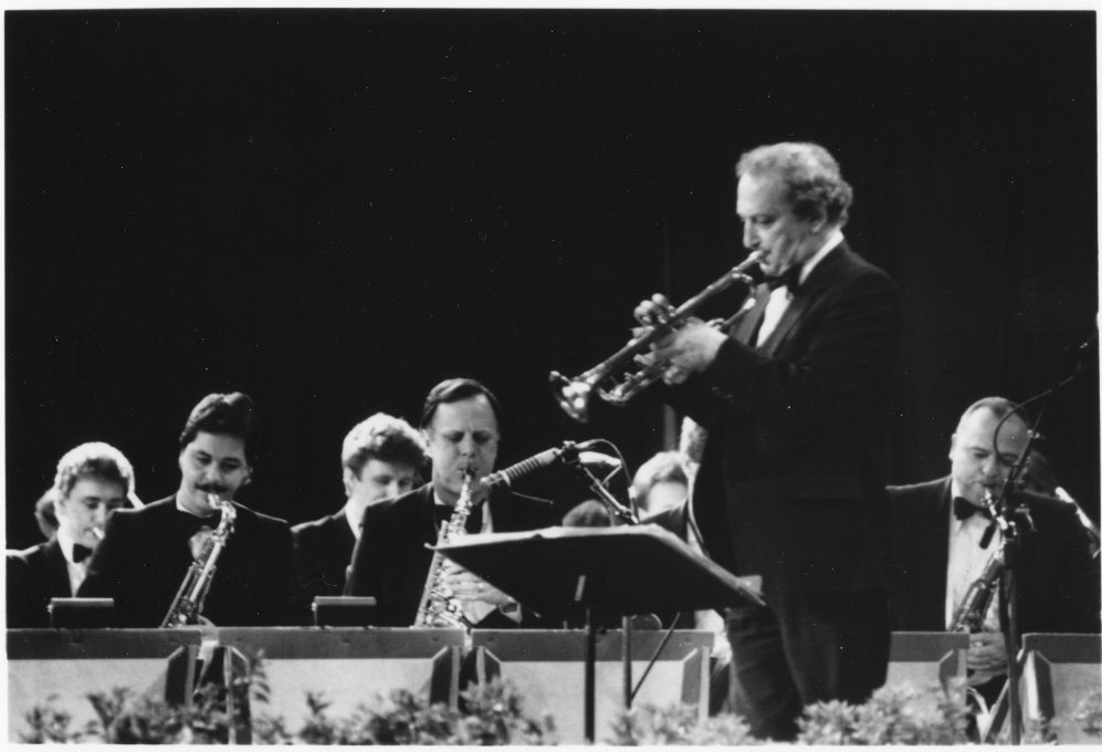 Man plays trumpet with a group of musicians at a formal concert