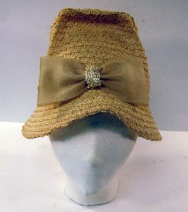 A mannequin head is modelling a straw-coloured hat with a matching bow tied around the brim. The head is looking straight on.
