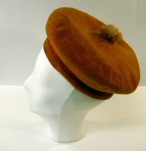 A mannequin head is pictured wearing a mustard yellow, wool beret.